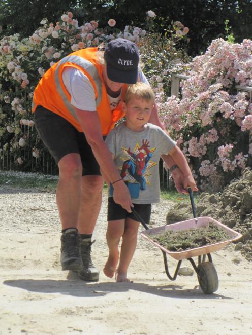 CODC planning and environment manager Louise van der Voort helps Roxburgh lad Will Riley (3) transport a barrowful of silt away from a flood-affected property during the "Shift that Silt" cleanup this weekend.